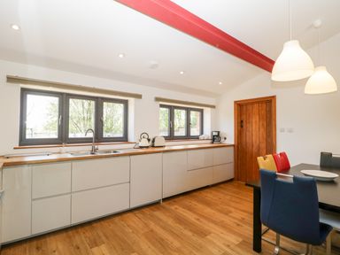A kitchen with wooden countertops white cabinets and multicolored chairs at The Stone Barn in Evercreech near Shepton Mallet