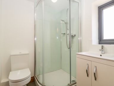 A bathroom with a toilet shower with glass doors and a sink with cabinet at The Stone Barn in Evercreech near Shepton Mallet