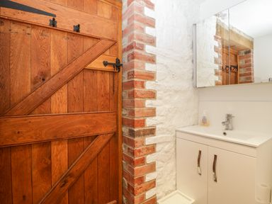 A bathroom with a wooden door a white sink cabinet and a mirrored medicine cabinet at The Stone Barn in Evercreech near Shepton Mallet