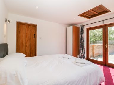 A bedroom with a bed and folded towels near wooden doors at The Stone Barn in Evercreech near Shepton Mallet