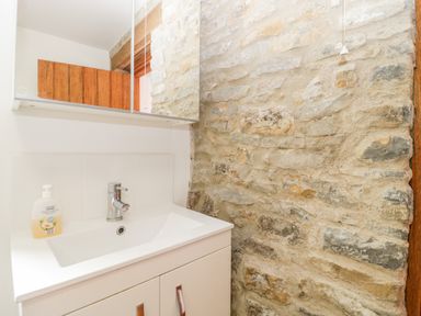 A bathroom sink with a faucet and soap dispenser next to a stone wall at The Stone Barn in Evercreech near Shepton Mallet