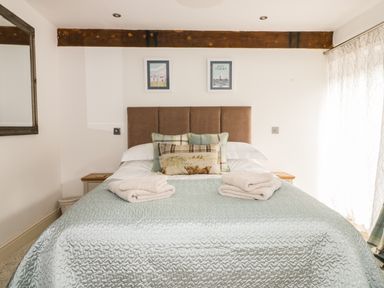 A bedroom with a bed with folded towels and pillows under a wooden beam at Cottage Val in Ravenscar