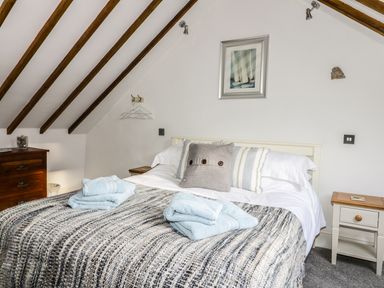 A bedroom with a bed with pillows and folded towels a wooden chest of drawers and a bedside table at Cottage Val in Ravenscar