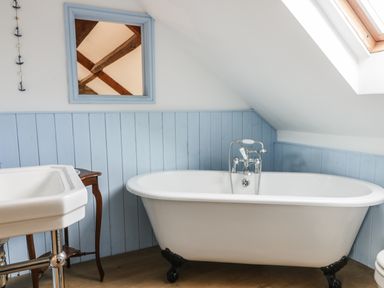 A bathroom with a freestanding bathtub sink and a mirror at Cottage Val in Ravenscar