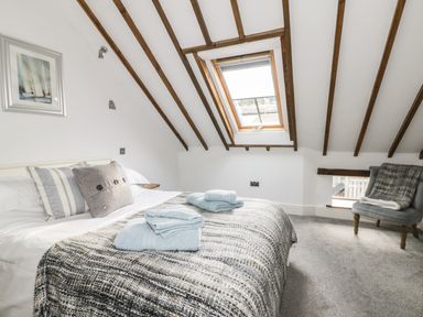 A bedroom with a bed with pillows and folded towels under a skylight window and a chair with a blanket at Cottage Val in Ravenscar