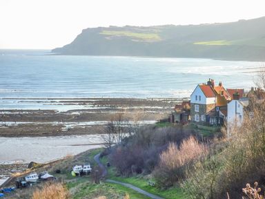 A coastal view with houses near the shoreline and boats on land at Cottage Val in Ravenscar
