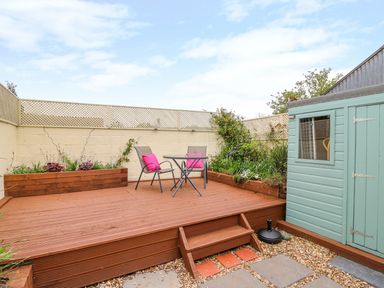 A wooden deck with two chairs and a table next to a light blue shed in a garden at Bank House in Capel Iwan near Newcastle Emlyn