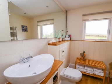 A bathroom with a white sink a toilet a wooden bench with towels and decor at Bank House in Capel Iwan near Newcastle Emlyn