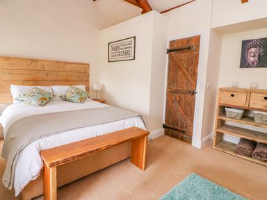 A bedroom with a wooden headboard bed two cushions a wooden door and a wooden shelf unit at Bank House Capel Iwan near Newcastle Emlyn