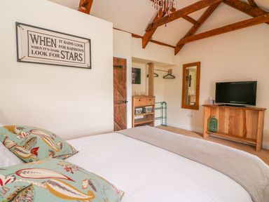 A bedroom with a bed pillows wall art wooden door wooden furniture and a television at Bank House in Capel Iwan near Newcastle Emlyn