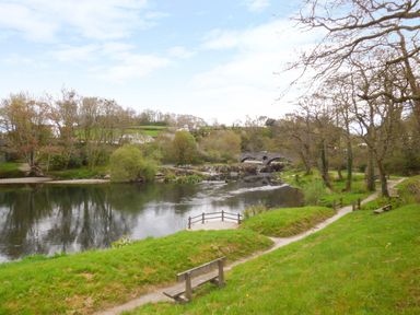 A river with stone bridge trees grass benches and walking paths at Bank House in Capel Iwan near Newcastle Emlyn