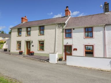 Two adjoining exterior houses with multiple windows and chimneys located on a sloped road at Bank House in Capel Iwan near Newcastle Emlyn