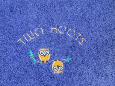 A blue towel embroidered with two owls on a branch and the text Two Hoots at Two Hoots in Northop