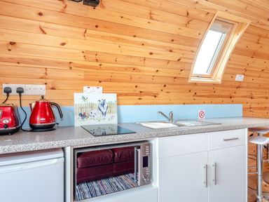 A kitchen counter with a red kettle toaster and microwave under counter at Ewe Two in Oakenholt near Northop