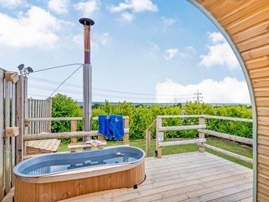 An outdoor hot tub on a wooden deck with a wood heater and blue towels at Ewe Two in Oakenholt near Northop