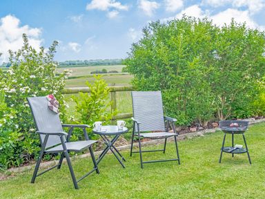 A garden with two chairs a small table with mugs and a barbecue grill at Ewe Two in Oakenholt near Northop