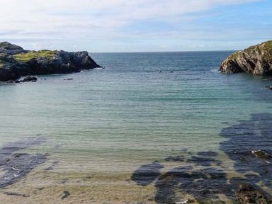 A seashore with clear water and rocky cliffs on both sides at Llety'r Bugail in Holyhead