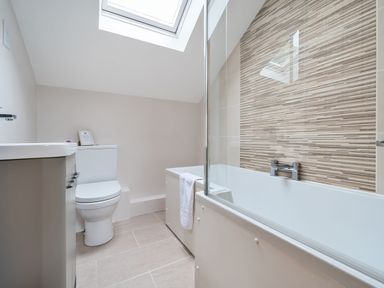 A bathroom with a toilet sink and bathtub under a skylight at Elm - Woodland Cottages in Bowness-on-Windermere