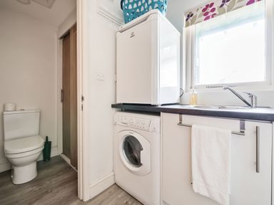 A utility room with a washing machine a small fridge a sink and a toilet at Cherry - Woodland Cottages in Bowness-in-Windermere