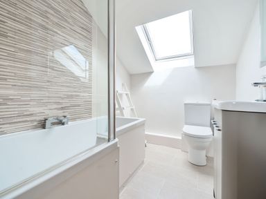 A bathroom with a bathtub, toilet, sink, skylight, and a ladder shelf at Cherry - Woodland Cottages in Bowness-in-Windermere