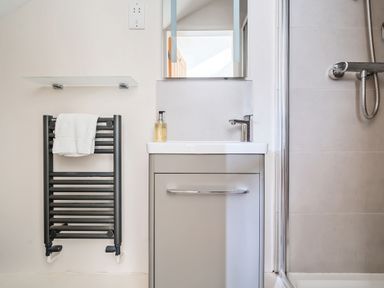 A bathroom with a sink and cabinet a towel rail with a towel and a shower at Cherry - Woodland Cottages in Bowness-in-Windermere