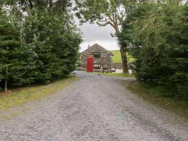 A stone building with a telephone box on a gravel path at Ash Lodge Pennington near Ulverston