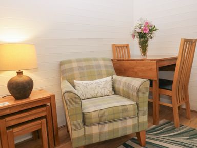 A snug area with an armchair and wooden table at Ash Lodge in Pennington near Ulverston