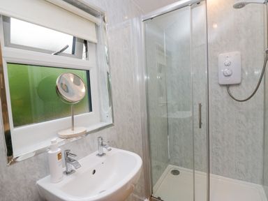 A bathroom with a sink, mirror, and shower at Ash Lodge in Pennington near Ulverston