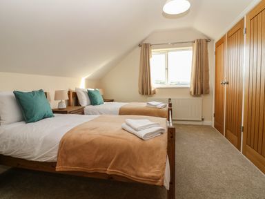 A bedroom with two single beds bedside tables window and wooden wardrobes at Rhos Helyg in Penysarn near Amlwch
