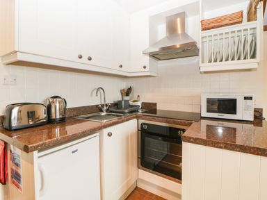 A kitchen with white cabinets brown countertops a toaster kettle oven microwave and sink at Nestling Barn Peter Tavy near Tavistock
