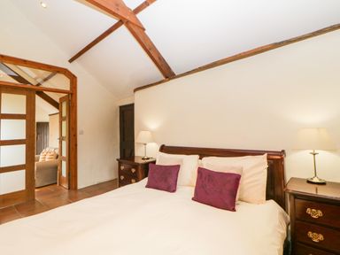 A bedroom with a double bed pillows lamps on bedside tables and wooden beams at Nestling Barn in Peter Tavy near Tavistock
