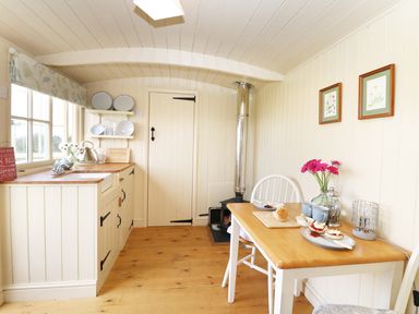 A small kitchen with wooden countertops a wood stove a table with food and flowers at Bramble Burlawn near Wadebridge