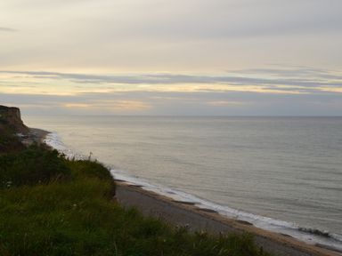 A coastline with grassy cliffs overlooking the sea under a cloudy sky at Oak Lodge in East Runton