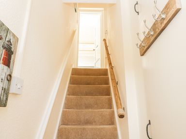 A carpeted staircase with wooden handrails leading to an open door at Oak Lodge in East Runton