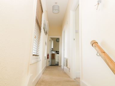 A hallway with windows on the left and doors on the right leading to a kitchen at Oak Lodge in East Runton