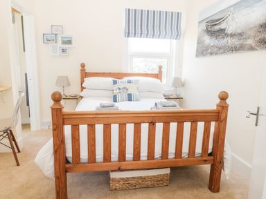 A bedroom with a wooden bed frame white bedding striped blinds and a boat painting at Oak Lodge in East Runton