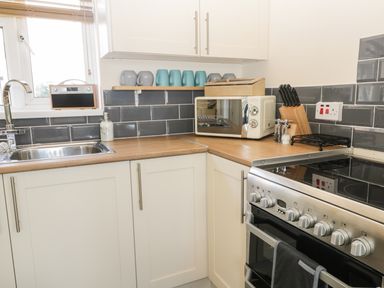 A kitchen countertop with a sink radio toaster microwave knife block and stove at Oak Lodge in East Runton