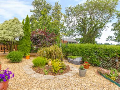A garden with gravel paths plants flowers and a wooden fence at Estuary View in Warkworth