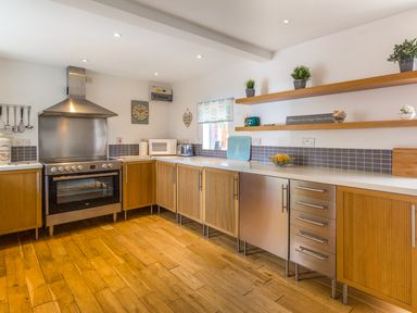 A kitchen with wooden cabinets stainless steel appliances and open shelves at Estuary View in Warkworth