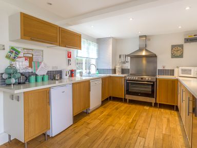 A kitchen with wooden cabinets white countertops a refrigerator stove microwave and sink at Estuary View in Warkworth