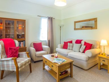 A living room with a sofa armchair coffee table cabinet and two lamps at Estuary View in Warkworth