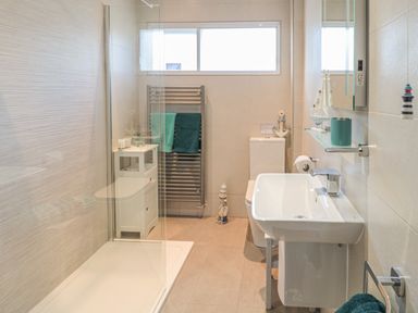A bathroom with a shower area sink toilet towel rack and small storage cabinet at Estuary View in Warkworth