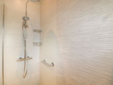 A shower area with a rain shower head soap holder and a grab bar at Estuary View in Warkworth