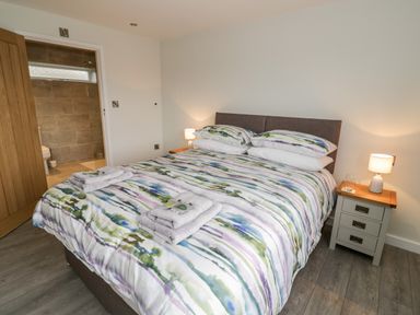 A bedroom with a double bed with striped bedding and bedside tables with lamps at Beechnut Cottage in Tewkesbury