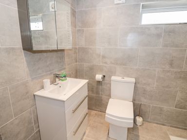 A bathroom with a white sink cabinet a toilet and a mirrored cabinet at Beechnut Cottage in Tewkesbury