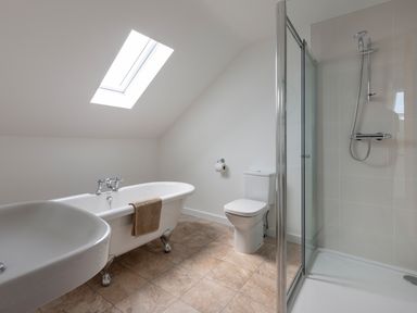 A bathroom with a bathtub shower toilet and sink under a skylight at Rocky Close in St Ives