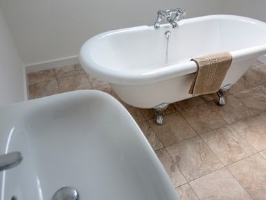 A bathroom with a white clawfoot bathtub and a white sink on tiled floor at Rocky Close in St Ives