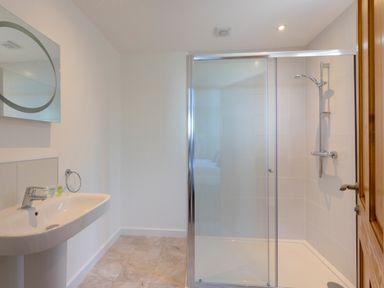 A bathroom with a wall-mounted sink and a glass-enclosed shower at Rocky Close in St Ives