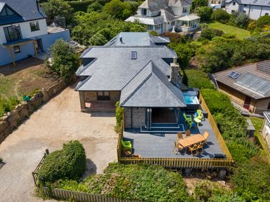 Aerial view of a house with a deck featuring outdoor seating and a hot tub surrounded by greenery at Rocky Close in St Ives