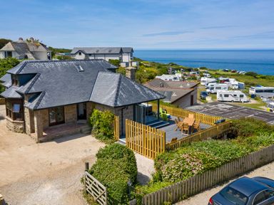 A stone house with a fenced patio and outdoor furniture near a caravan park by the sea at Rocky Close in St Ives